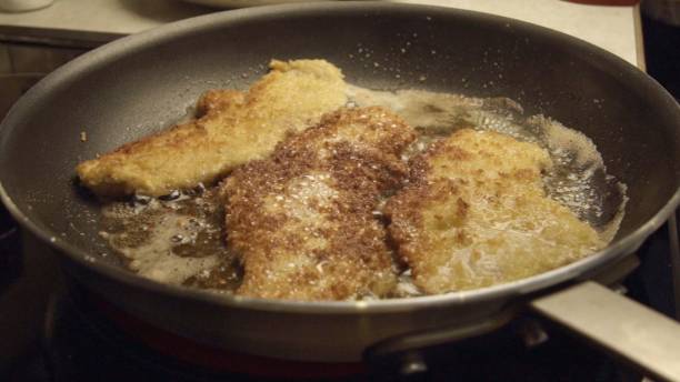istock Pork Cutlets or Schnitzel Breaded and Frying in a Skillet 986909720