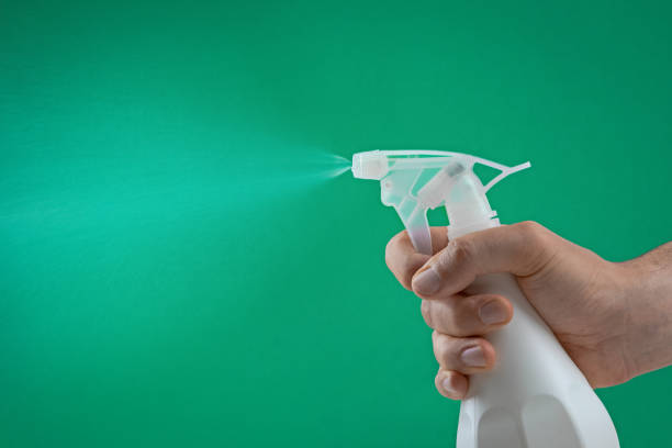 istock hand squeezing the trigger of a spray bottle spraying water mist on a green background 986928608