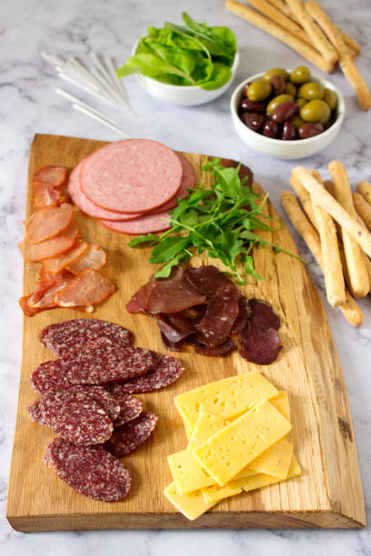 istock Appetizer table for wine or beer with sausages, dried meat and cheese, served with grissini, herbs and olives. 986934774