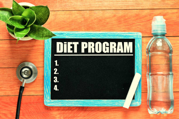 istock DIET PROGRAM handwritten with white chalk on a blackboard on wood background 986946994