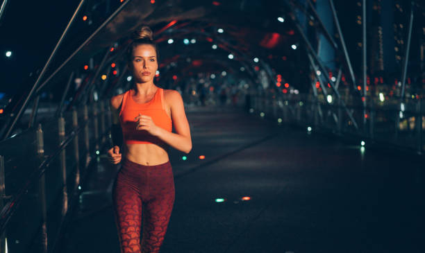 young woman jogging at night on the bridge - night running imagens e fotografias de stock