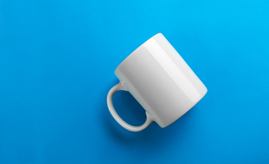 Flipped white mug on blue background