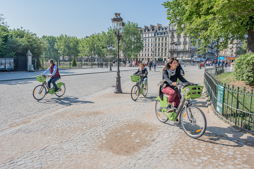 Paris / France - May 19, 2018: Friends ride bikes over cobblestone streets on the Isle de la Cite, near Notre Dame Cathedral.