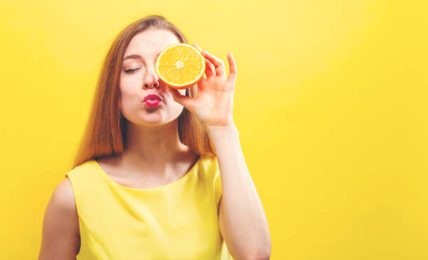 istock Happy young woman holding a half orange 986986580