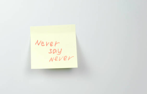 istock Note on yellow sticker paper sheets with motivation words never say never. 987006388