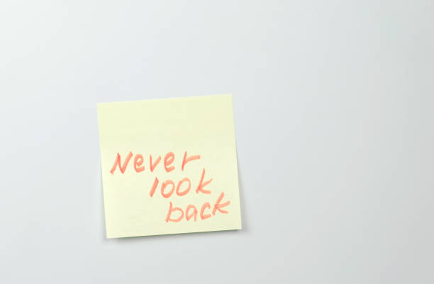 istock Note on yellow sticker paper sheets with motivation words never look back. 987007536