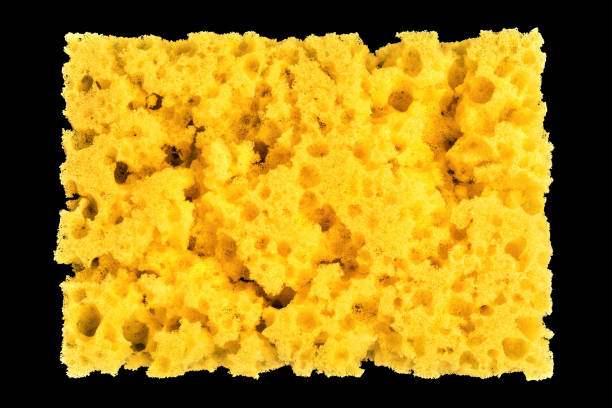 istock worn yellow sponge for washing dishes on black background, abstract background 987007620