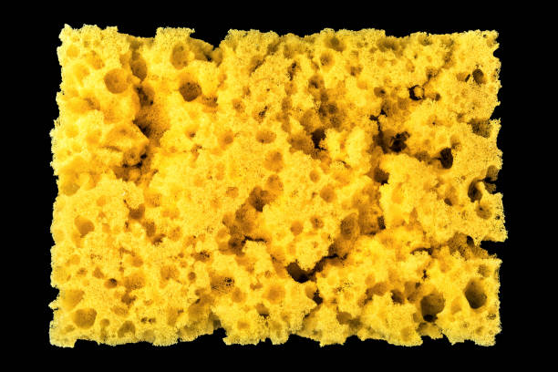 istock worn yellow sponge for washing dishes on black background, abstract background 987009738