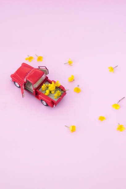 istock A red retro car with yellow flowers on a pink background 987009770