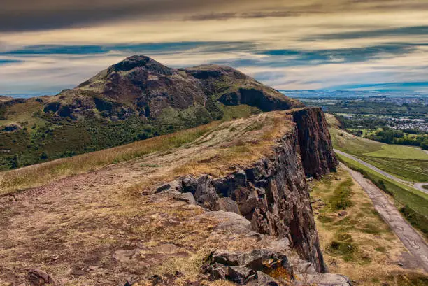 Photo of Beautiful landscape of Arthur's Seat mountain in Scotland with path on the cliff and Edinburgh city in the background