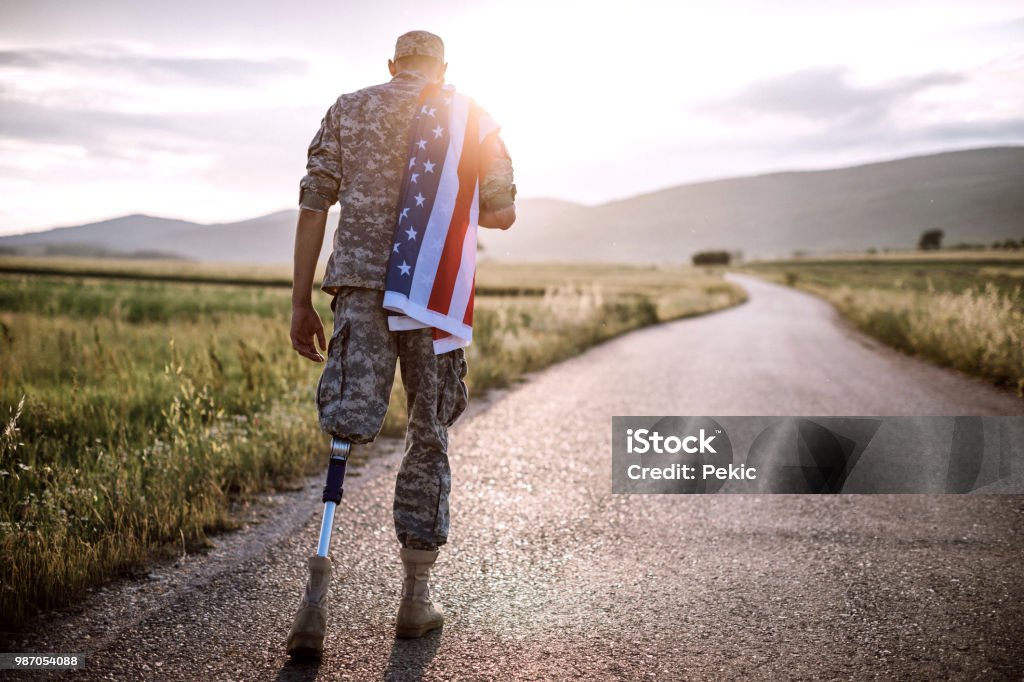 American Amputee Soldier On Road Rear View Of Young Amputee Soldier Walking Road Wearing American Flag Veteran Stock Photo