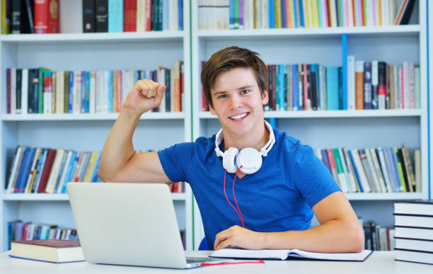 istock Portrait of happy student while reading book in school library. Study lessons for exam. Hard worker and persistance concept. 987063988