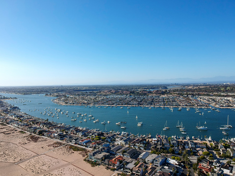 An aerial shot at 330 feet/100 meters looking out over the Newport skyline, the Balboa Peninsula and the Newport Bay full of boats. Captured in Southern California from an aeiral drone.