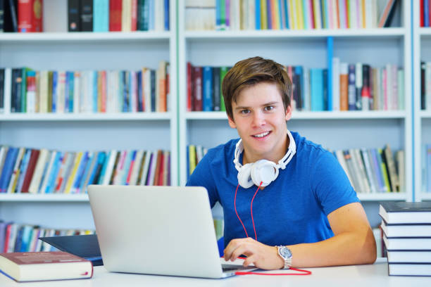 istock Portrait of happy student while reading book in school library. Study lessons for exam. Hard worker and persistance concept. 987111206