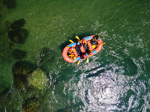 Drone point of view of a group men and women rafting in a calm river
