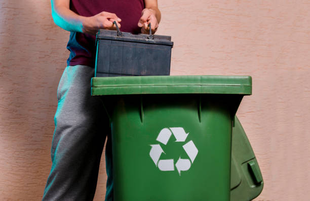 istock Man throwing old car battery in recycle bin. 987126514