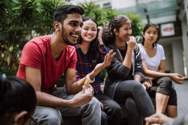 Group Of Students Joking And Getting To Know Each Other Multi Ethnic Group Of Students Joking And Getting To Know Each Other Better On Lunch Break in University Yard male chinese student stock pictures, royalty-free photos & images