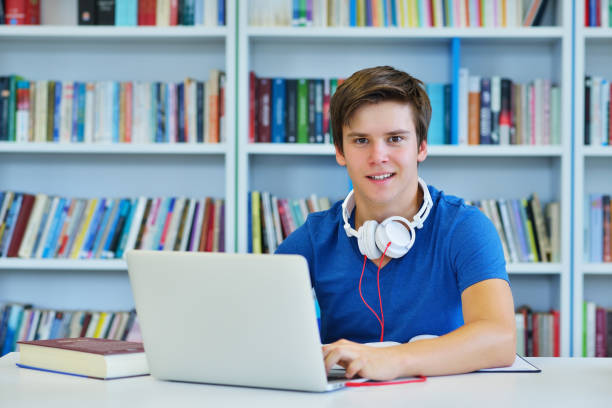 istock Portrait of happy student while reading book in school library. Study lessons for exam. Hard worker and persistance concept. 987137868