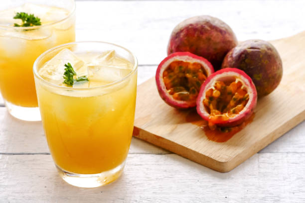 A glass of juice and fresh passion fruit on wooden table