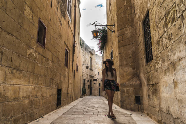 女性は、イムディーナ、マルタの古代都市の通りを歩く - イムディーナ ストックフォトと画像
