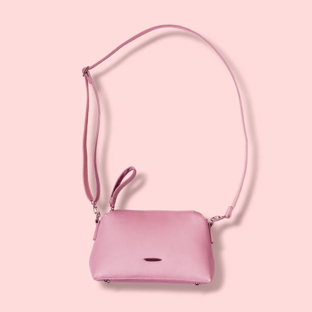 istock Ladies pink pastel handbag with long strap on pink background 987223588