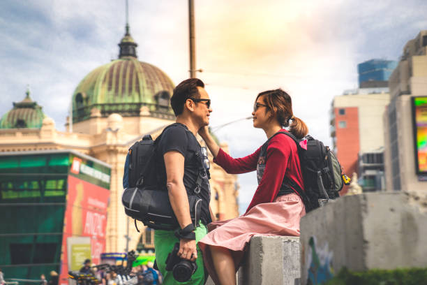 a lady backpackers smiling touching a man backpacker in front of Flinder train station in Melbourne, 11/05/18 stock photo