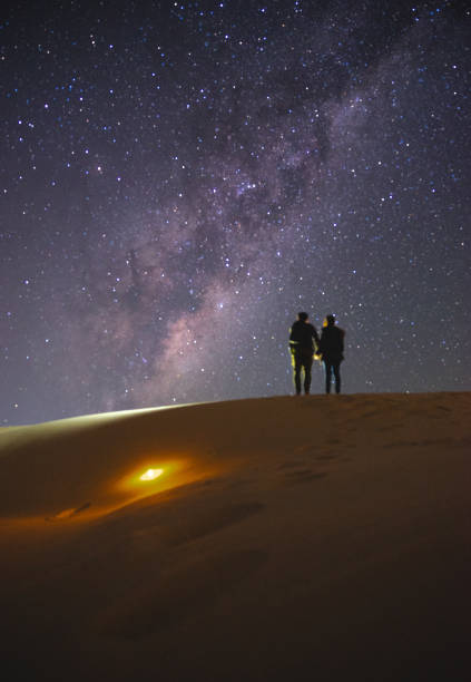 Landscape with Milky Way. Night sky with stars and silhouette of a standing  couple on sand hill. stock photo