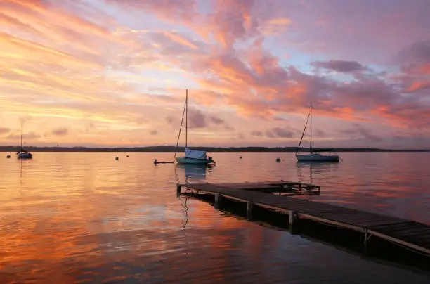 Amazing summer evening landscape with group of drifting yachts on a lake Mendota during spectacular sunset. Bright sky reflects in the lake water. Madison, WI, Midwest USA.