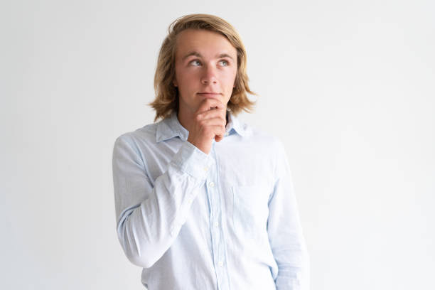 istock Dreamy young man touching chin and looking away 987268764