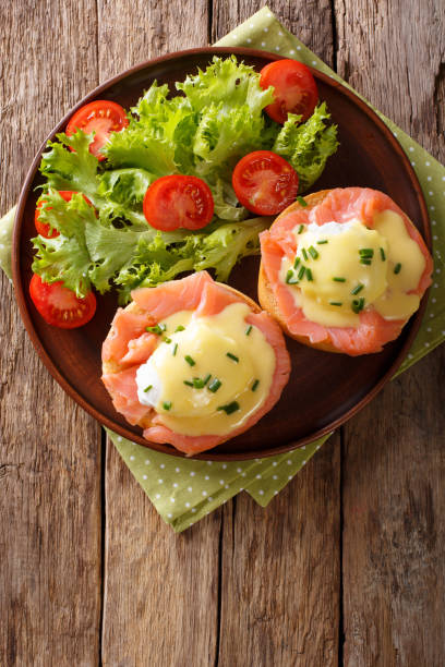 istock hearty breakfast: poached eggs with salmon and hollandaise sauce close-up. Vertical top view 987269926