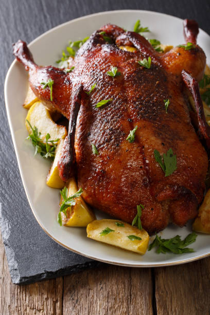 istock Baked duck with apples close-up on a plate. vertical 987275192