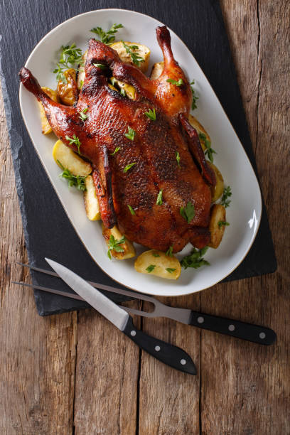 istock Home-baked duck stuffed with apples close-up on a plate. Vertical top view 987293550