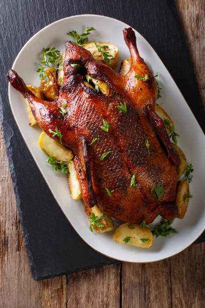 istock Beautiful food: baked whole duck with apples close-up on a platter. Vertical top view 987294414