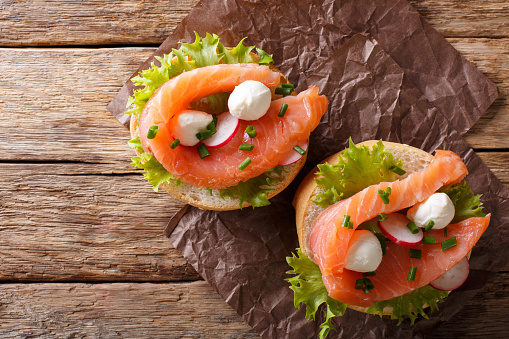 Sandwiches with salted salmon, mozzarella, frisee, onion and radish close-up on the table. horizontal view from above