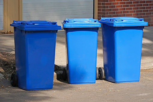 Blue garbage cans on the street in a row
