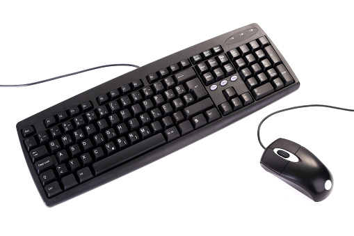 Computer equipment place on a richly grained rosewood table. Displayed are a bluetooth wireless keyboard and mouse that works on Bluetooth Technology. At the top of the image is a mobile phone and a ballpoint pen. Adequate copy space for designers has been provided for Designers. Note to inspector: All logos and key indicators have been removed in photoshop.