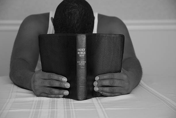 Coming to Jesus moment (Religion) Man with head down and bible in hands. methodist stock pictures, royalty-free photos & images