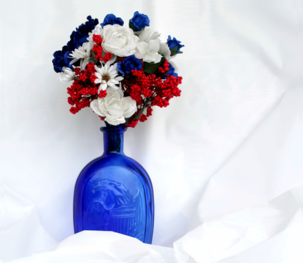 Red, white and blue flowers on silk in a blue bottle etched with an American eagle.  
