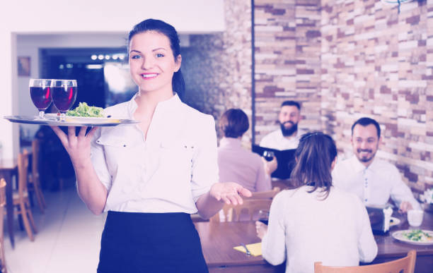 istock Cheerfull female waiter carrying order for visitors 987342478