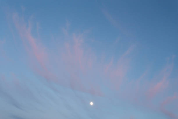 istock Moon at sunset in the blue sky with pink clouds 987355286