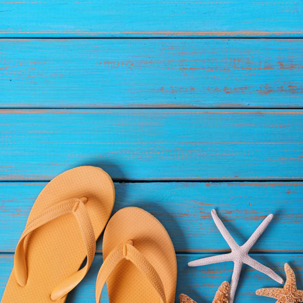 istock Flip flops star fish summer seashore blue wood background 987359520