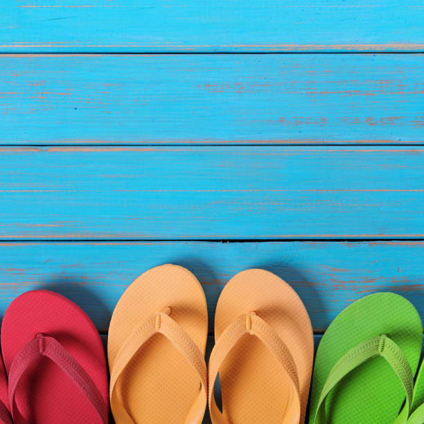 istock Flip flops in a row blue beach wood background 987359856