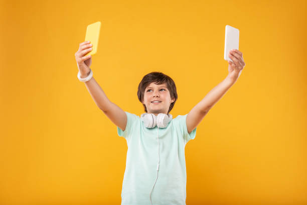 istock Exuberant schoolboy having two phones 987360002
