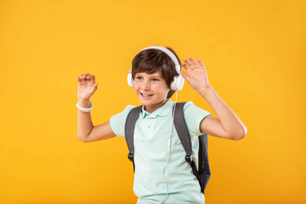 istock Joyful schoolboy listening to music 987364998