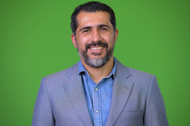 istock Handsome Persian bearded businessman against green background 987365562