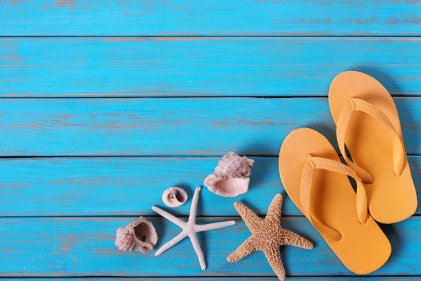 istock Flip flops starfish old distressed bright blue beach wood background 987366002