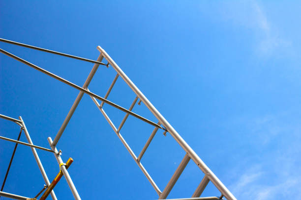 istock Silhouette of construction workers on scaffold working under a blue sky 987371092