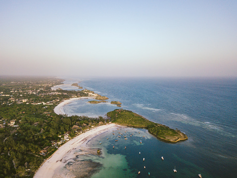 Aerial drone shot of Watamu Beach and Town with anchored boats, sandy beaches and lush forest hugging the coast.