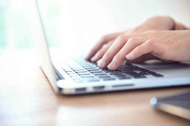 istock woman's hands typing on a laptop on a wooden desk. 987379916