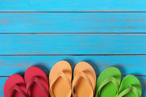 istock Flip flops in a row old weathered blue beach wood background 987383054